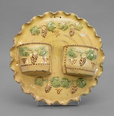 a yellow plate with grapes on it on a stand