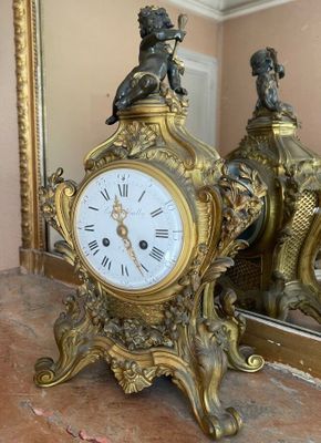 a clock that is sitting on a table in front of a mirror