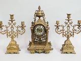 trois bougeoirs dorés et une horloge sur fond blanc