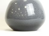 a black and white vase sitting on a white surface