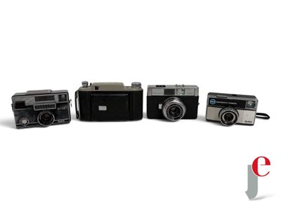 several old cameras are lined up in a row on a white surface
