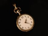 a close up of a pocket watch on a black surface