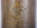 an old brass vase with a label on it