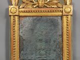 un cadre doré sur lequel est posé un miroir, posé sur une surface grise