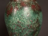 a green and red vase sitting on a wooden table