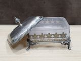 a silver plate with a lid on a wooden table