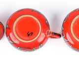 two red teapots sitting next to each other on a white surface
