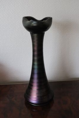 a black vase sitting on a wooden table next to a white wall