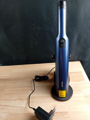 une bouteille de vin bleue posée sur une table en bois, à côté d'une assiette de présentation