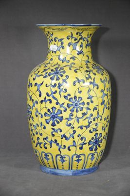 un vase jaune orné de fleurs bleues sur fond gris