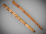 two wooden walking canes with carvings on them sitting on a table