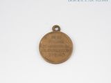 an old bronze medal with writing on it sitting on a white surface