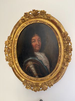 a painting of a man in a gold frame hanging on a wall