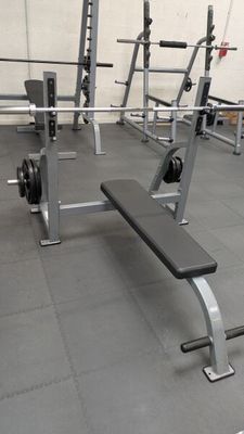 a gym with a bench and weights in the middle of the room