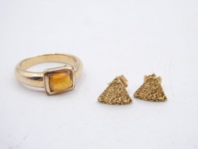a close up of a ring and two pieces of jewelry on a white surface