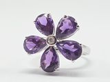 un gros plan d'une bague ornée de pierres violettes sur fond blanc