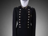 a black military jacket with gold buttons and a hat on a mannequin stand
