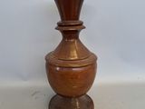 a brown vase sitting on a table with a white wall in the background