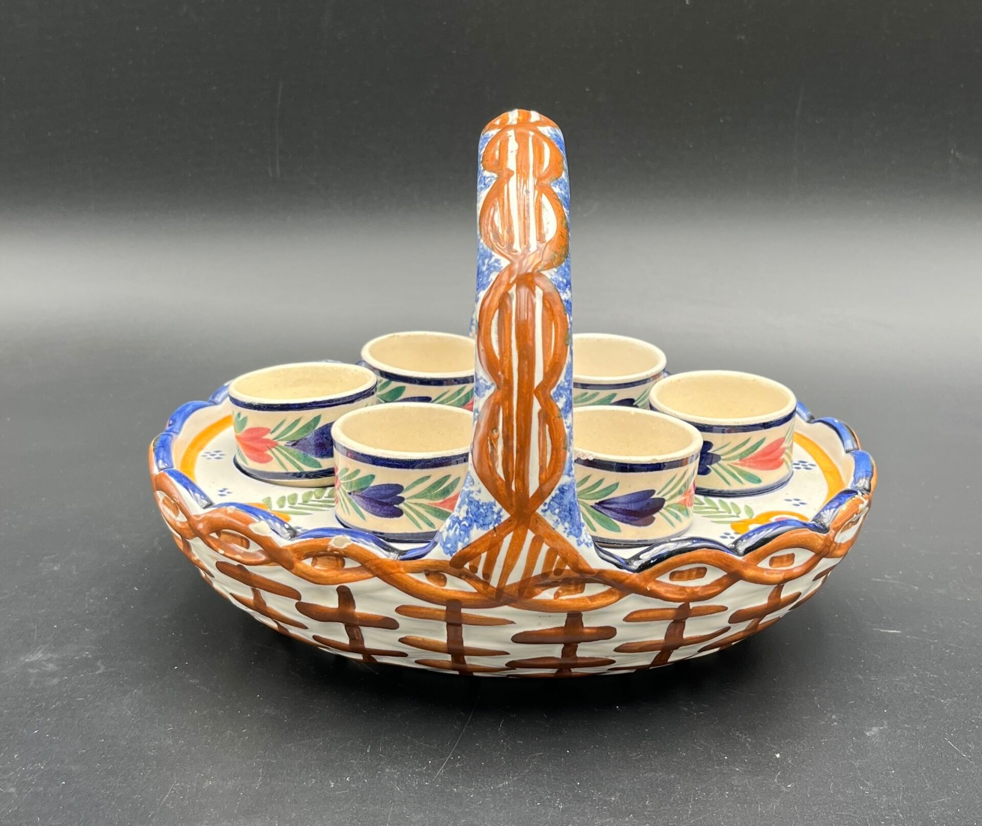 VERLINGUE-BOLLORE QUIMPER Un panier muni de six coquetiers en faïence à fond blanc et décor polychrome fleuri et de b...