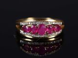 a close up of a gold ring with ruby stones and diamonds