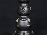 a close up of a black vase with three faces on it