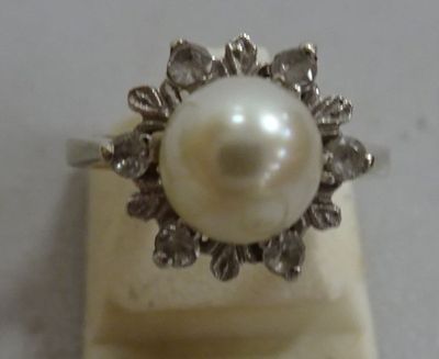 a pearl and diamond ring sitting on top of a marble block