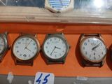 five different clocks on display in a display case