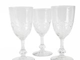three clear wine glasses sitting next to each other on a white surface