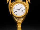 un vase doré orné d'une horloge, sur fond noir