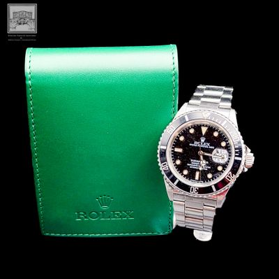 une montre posée à côté d'un portefeuille vert