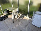 a chair and a table on a patio next to a trash can