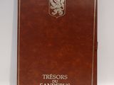 un vieux livre marron orné d'un blason, posé sur une surface blanche