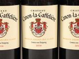three bottles of red wine are lined up on a shelf
