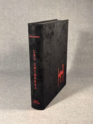 an old book with red writing on it sitting on a gray surface