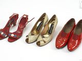 trois paires de chaussures rouges et dorées sont alignées sur une surface blanche