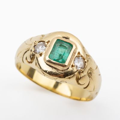 a close up of a gold ring with an emerald and diamonds