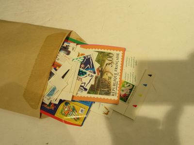 un sac en papier brun rempli de timbres et l'ombre d'une personne