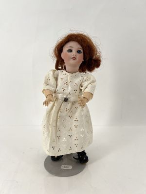 poupée en porcelaine représentant une femme aux cheveux roux vêtue d'une robe blanche