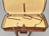 a brown suitcase with a brown handle on a gray surface