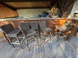 four wicker chairs sitting on a wooden deck near a bar