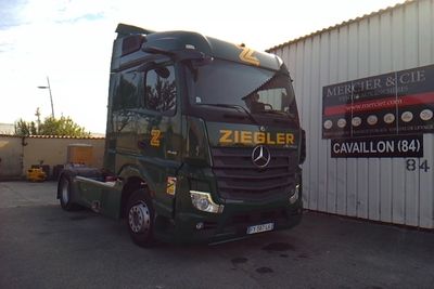 un grand camion vert garé devant un immeuble