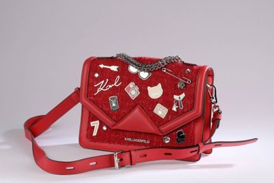 someone is holding a red purse with a bunch of charms on it