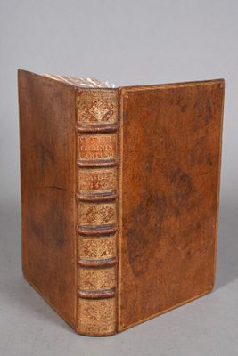 an old book with a brown leather cover sitting on top of a table