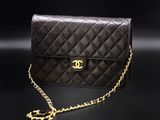 a black chanel bag with gold chain on a black background