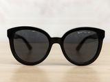 black cat eye sunglasses on a wooden table with a white background