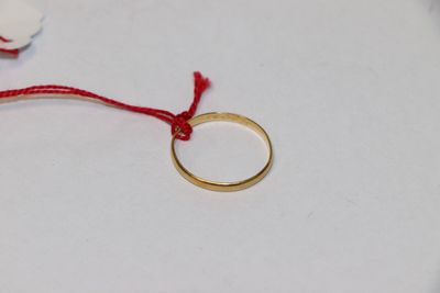 une bague en or à laquelle est attaché un cordon rouge