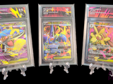 Trois cartes Pokémon se trouvent dans un sachet en plastique transparent sur fond noir.