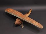 une vieille maquette en bois représentant un petit avion, posée sur une surface noire