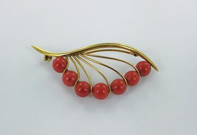 gold plated brooch with red beads on a white background