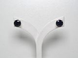 une paire de boucles d'oreilles à clous ornées de diamants noirs, présentées sur un socle blanc